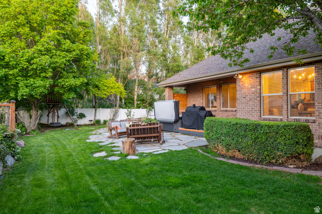 6208 West Bull River Road Highland, UT 84003 - Photo 59 of 90 Expansive backyard featuring a stone patio, mature trees, a privacy fence, and a brick exterior with multiple windows