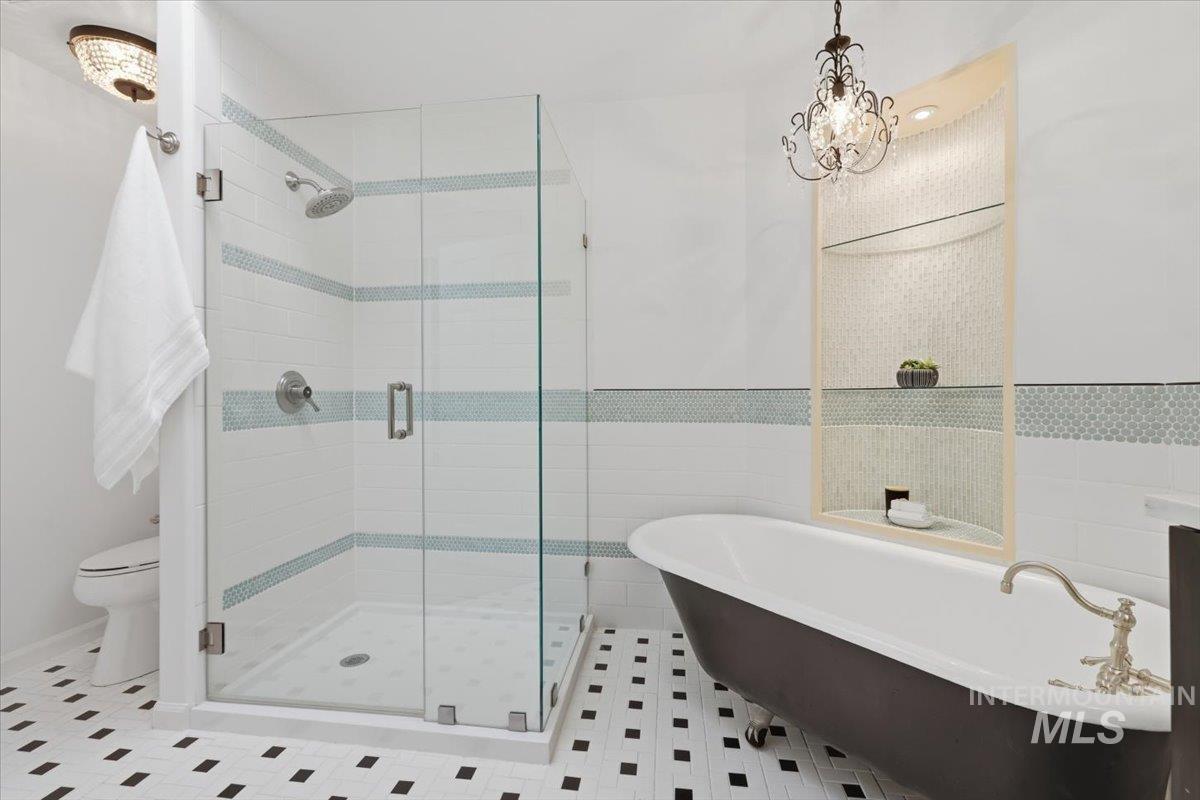 2075 North Springland Place Boise, ID 83713 - Photo 24 of 49 Bathroom featuring a glass-enclosed shower with tile accents, a freestanding clawfoot tub, and a decorative chandelier