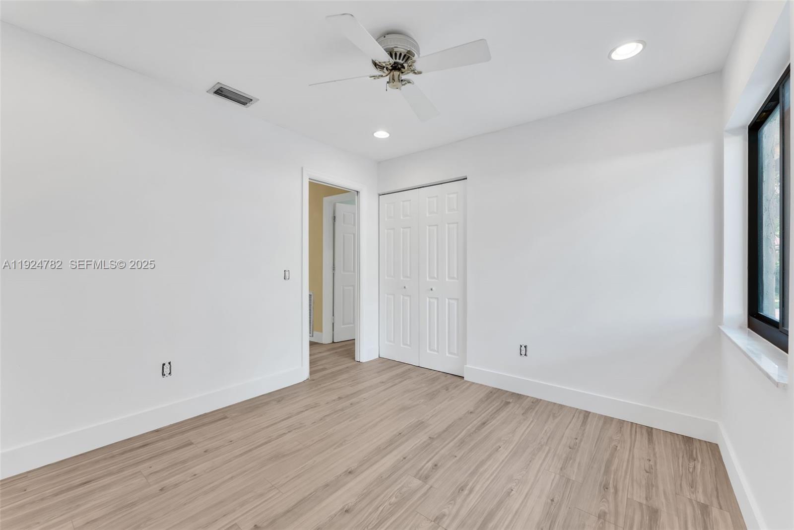 11525 Southwest 135th Court Miami, FL 33186 - Photo 17 of 42 an empty room with wooden floor ceiling fan and windows