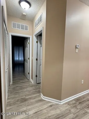 a view of a hallway with wooden floor and closet