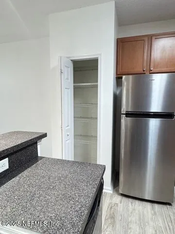 a kitchen with a refrigerator and wooden floor