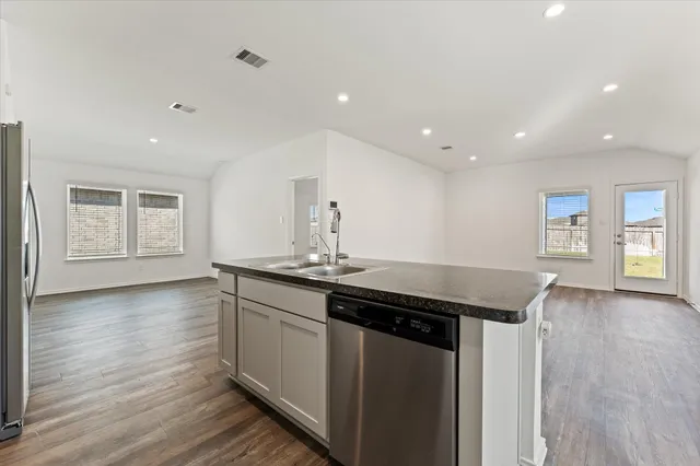 a kitchen with stainless steel appliances granite countertop a sink and wooden floor
