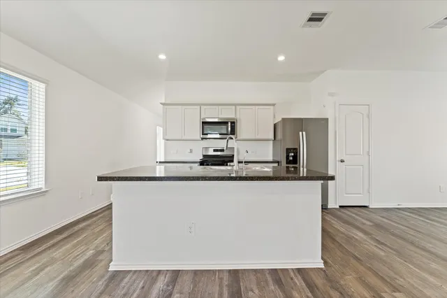a kitchen with stainless steel appliances granite countertop a stove a sink and a refrigerator
