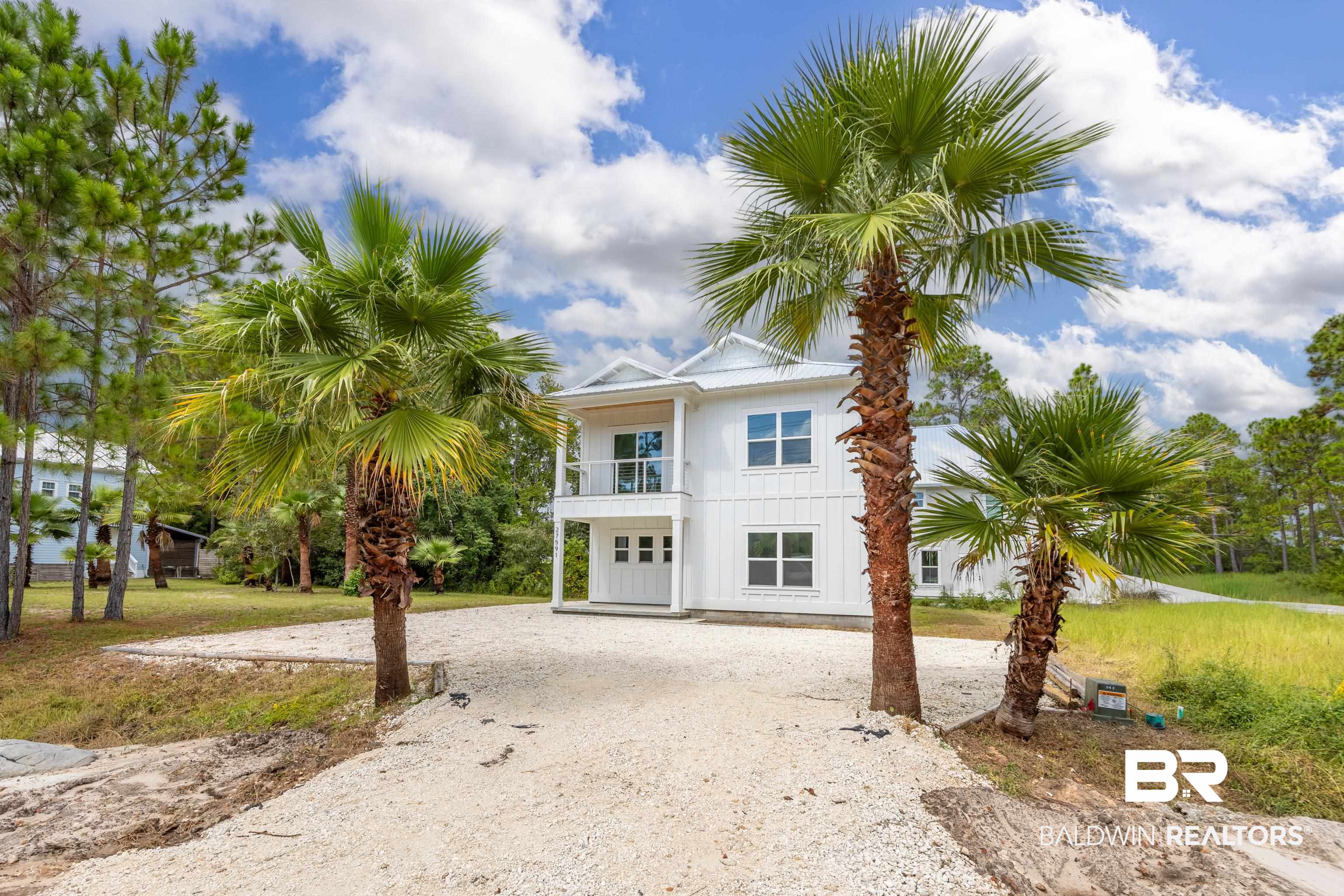 27591 Canal Road Orange Beach, AL 36561 - Photo 2 of 51 Coastal inspired home with a balcony, driveway, board and batten siding, and a front lawn