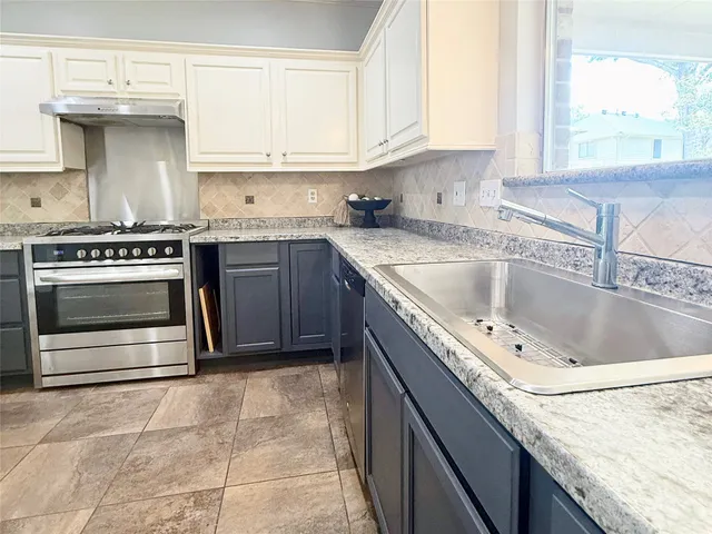 a kitchen with granite countertop a oven and a white cabinets