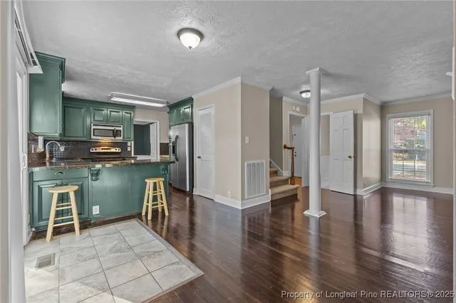 a room with kitchen island a large window and stainless steel appliances