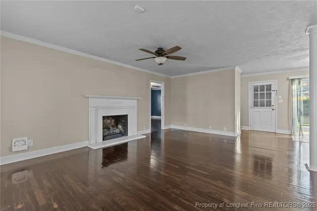 an empty room with wooden floor a ceiling fan and windows