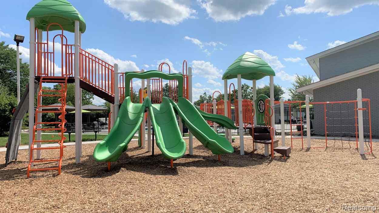 92 Normandy Drive Howell, MI 48843 - Photo 22 of 24 Recreational playground area featuring multiple slides, climbing structures, and a wood chip surface