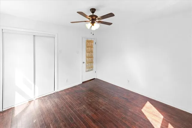 an empty room with wooden floor and ceiling fan