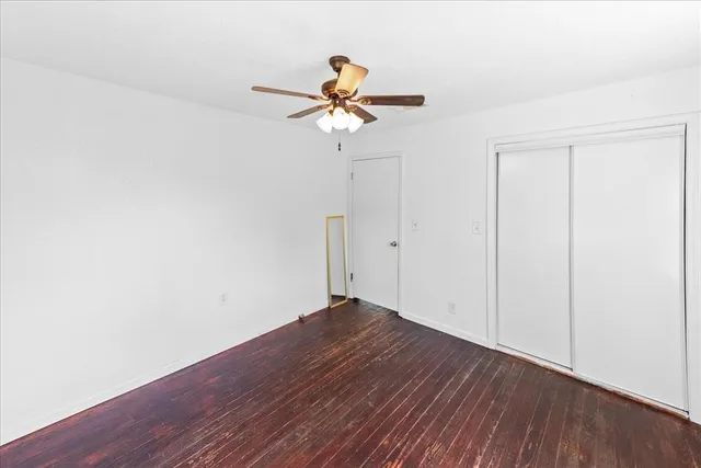 a view of a room with wooden floor ceiling fan and window