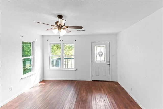 a view of an empty room with wooden floor and a window