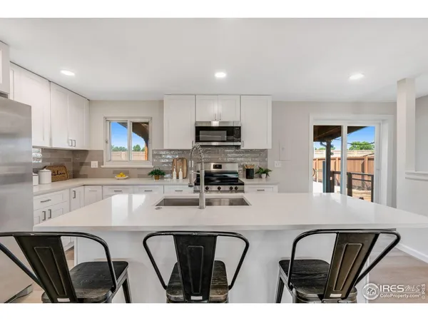 a kitchen with stainless steel appliances kitchen island granite countertop a stove top oven a sink a refrigerator with a dining table and chairs