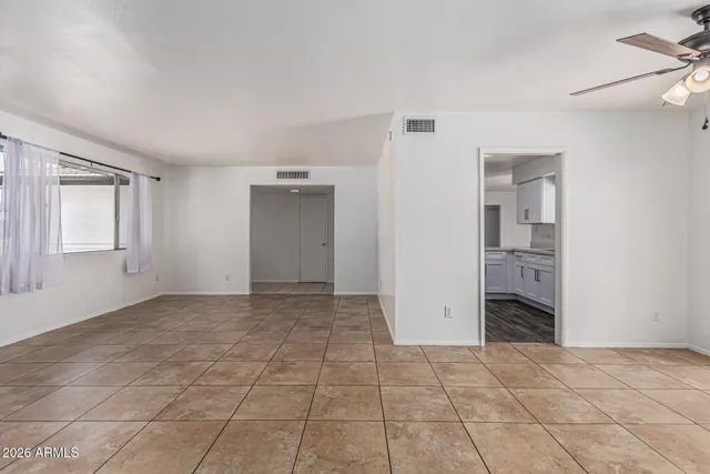 a view of an empty room with window and a kitchen