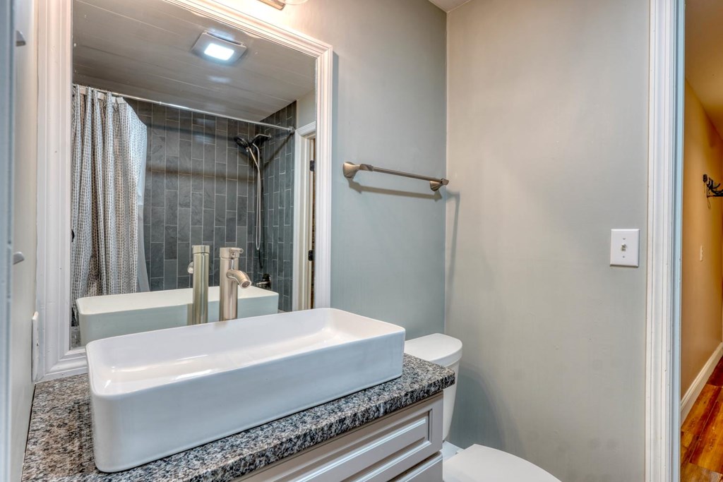 45 Mountain Stream Road Murphy, NC 28906 - Photo 24 of 33 a bathroom with a granite countertop sink a toilet a mirror and shower