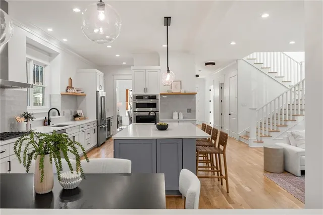 a kitchen with stainless steel appliances kitchen island granite countertop a table chairs in it and wooden floors