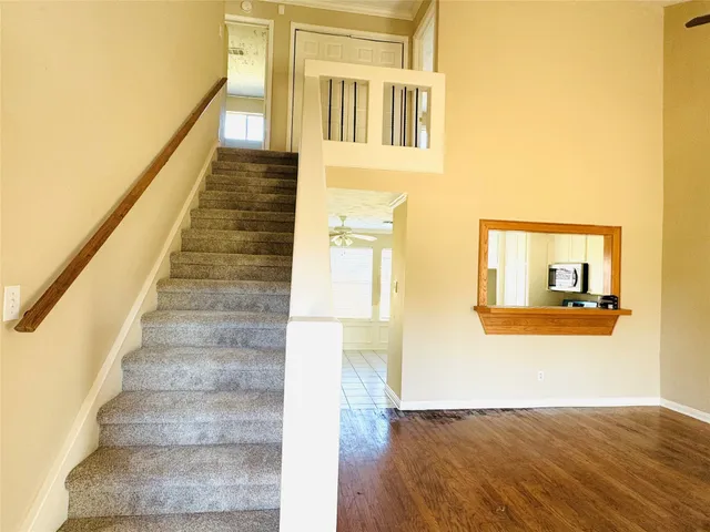 a view of a hallway with wooden floor and staircase