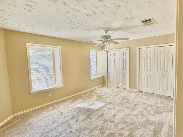 a view of an empty room with chandelier fan and fire place