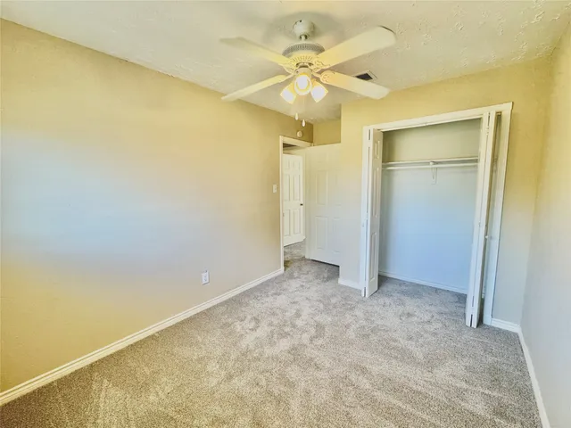 an empty room with a ceiling fan and a shower