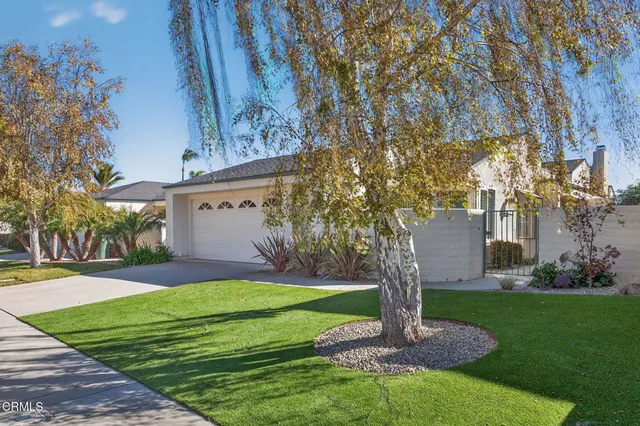 a front view of a house with a garden and trees