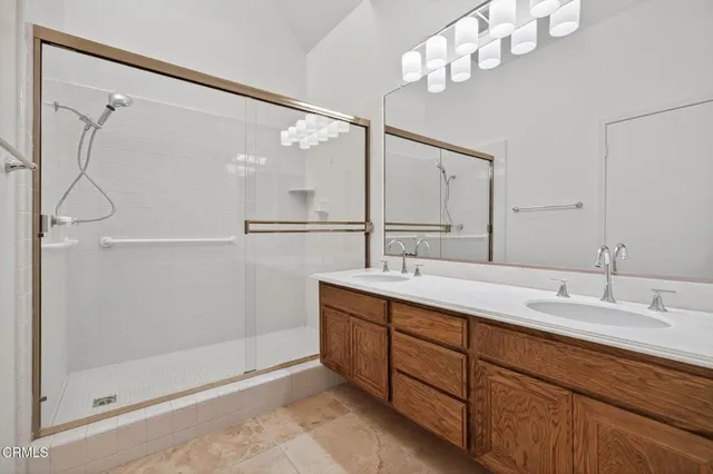a bathroom with a double vanity sink mirror and shower