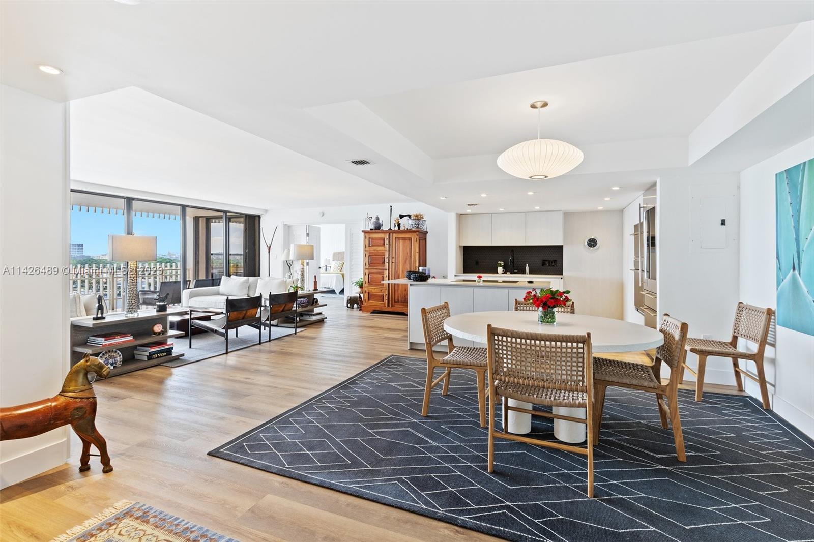 a living room with furniture kitchen view and a large window