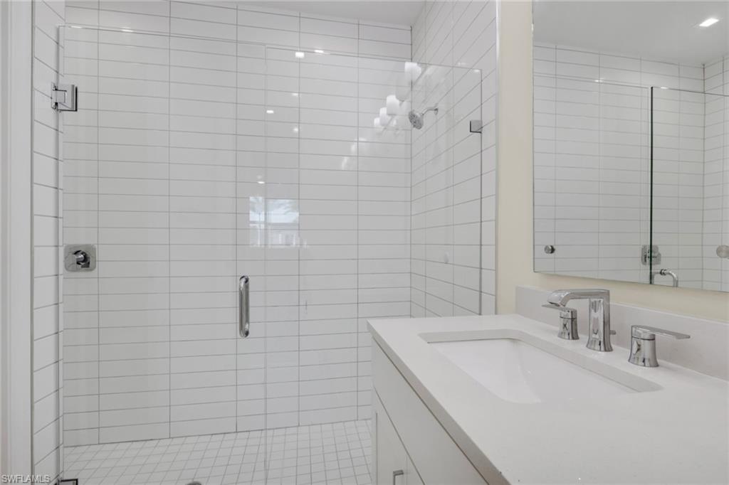 7540 Carnegie Way Naples, FL 34119 - Photo 22 of 40 a bathroom with a sink a shower and a mirror