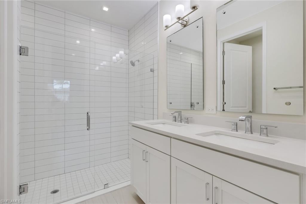 7540 Carnegie Way Naples, FL 34119 - Photo 23 of 40 a bathroom with a shower sink and mirror