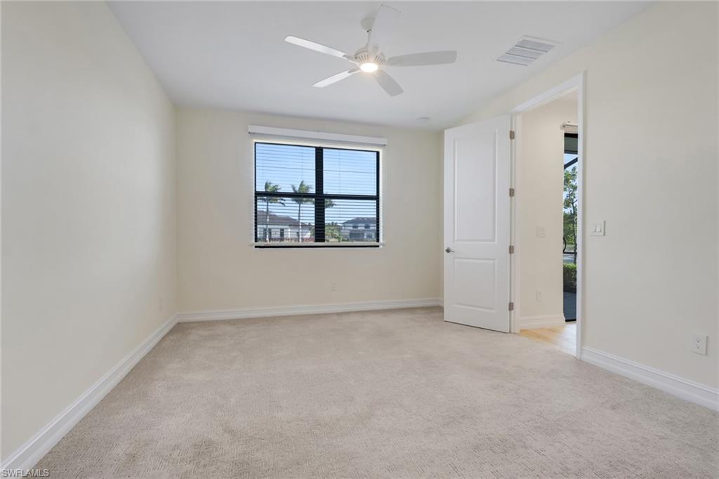 7540 Carnegie Way Naples, FL 34119 - Photo 25 of 40 an empty room with windows and a ceiling fan