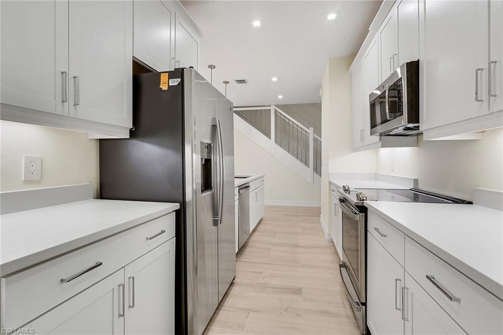 7540 Carnegie Way Naples, FL 34119 - Photo 35 of 40 a kitchen that has a lot of cabinets and wooden floor