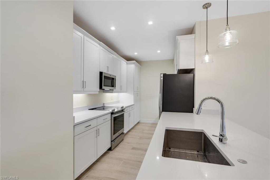 7540 Carnegie Way Naples, FL 34119 - Photo 37 of 40 a kitchen with a sink a microwave a stove and refrigerator