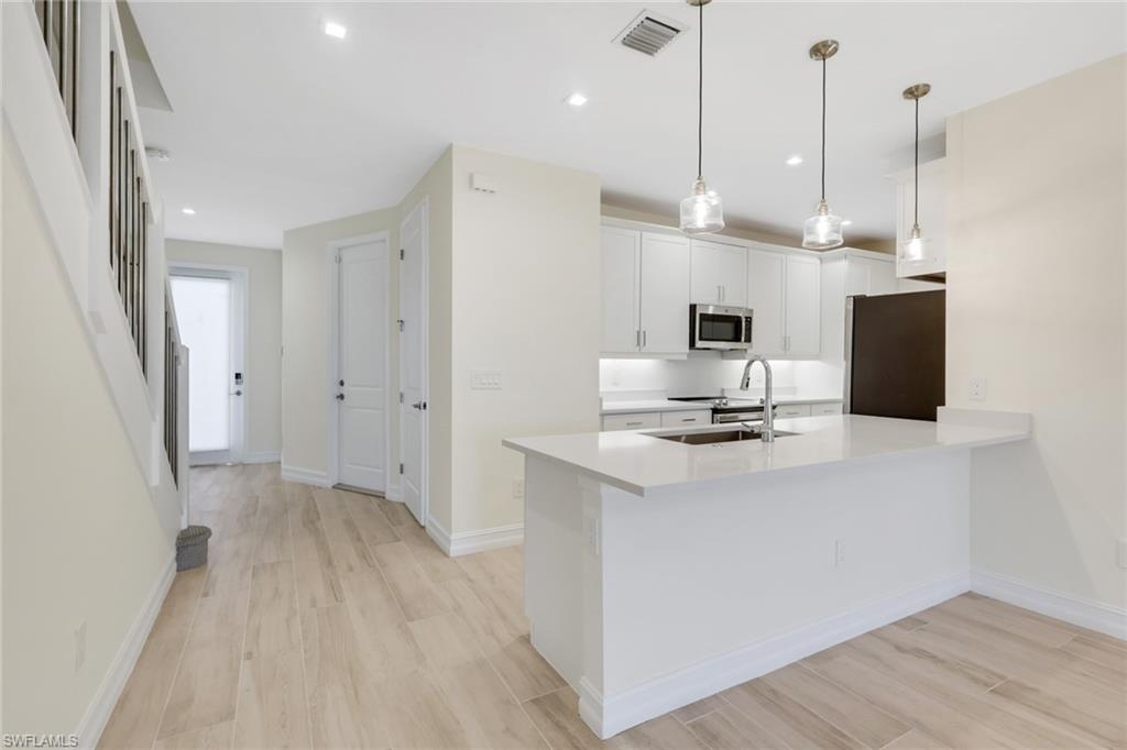 7540 Carnegie Way Naples, FL 34119 - Photo 38 of 40 a view of a kitchen with a sink a microwave and wooden floor