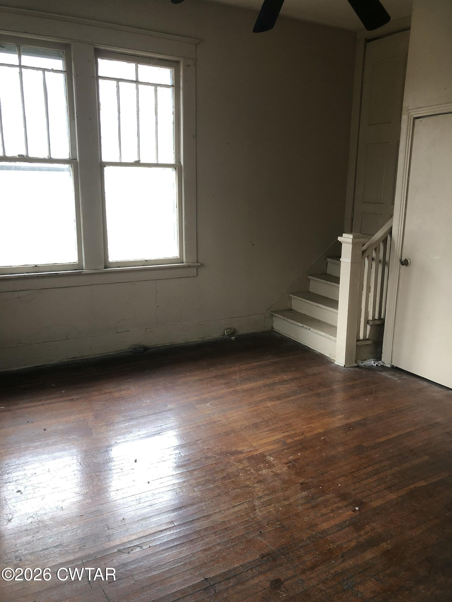 126 McCorry Street Jackson, TN 38301 - Photo 3 of 8 an empty room with wooden floor and windows