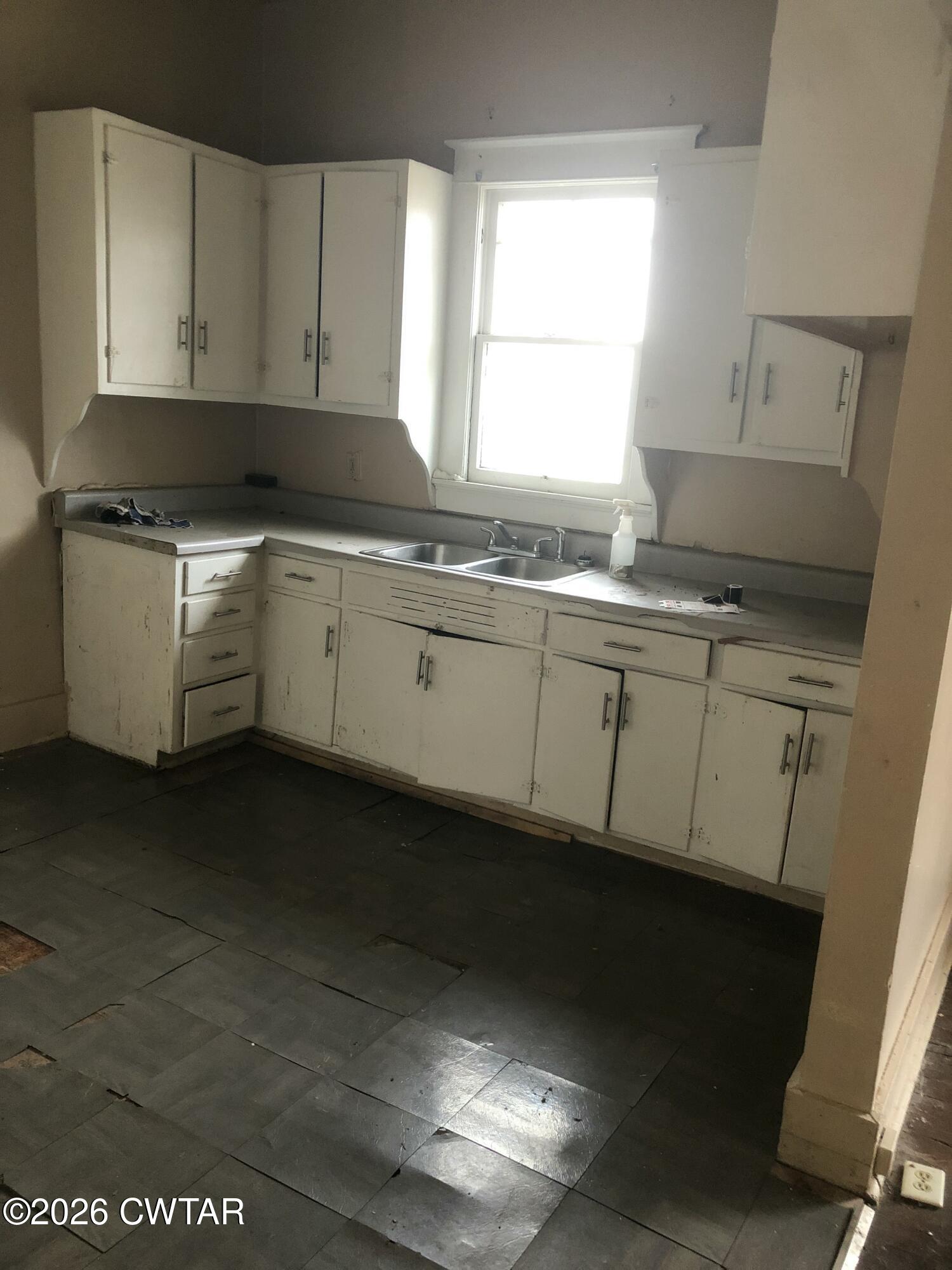 126 McCorry Street Jackson, TN 38301 - Photo 4 of 8 a kitchen with granite countertop white cabinets sink and window