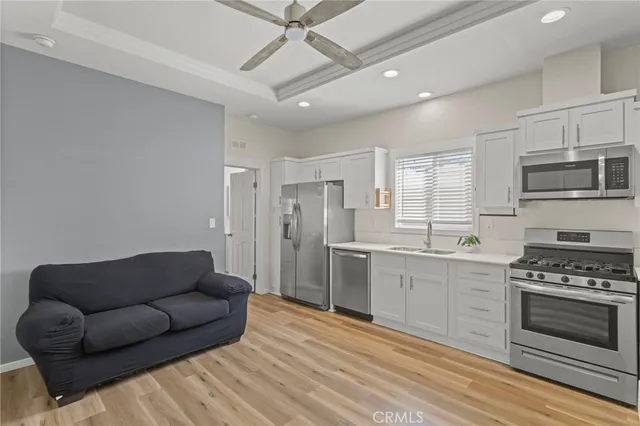 a large white kitchen with stainless steel appliances granite countertop a stove a sink and a refrigerator