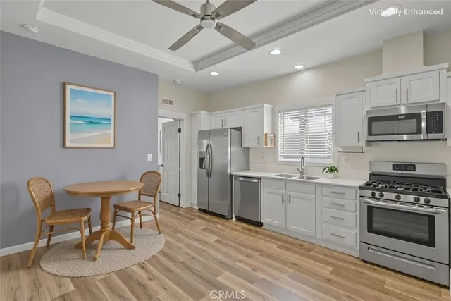 a kitchen with stainless steel appliances a stove a sink dishwasher a refrigerator and a dining table with wooden floor