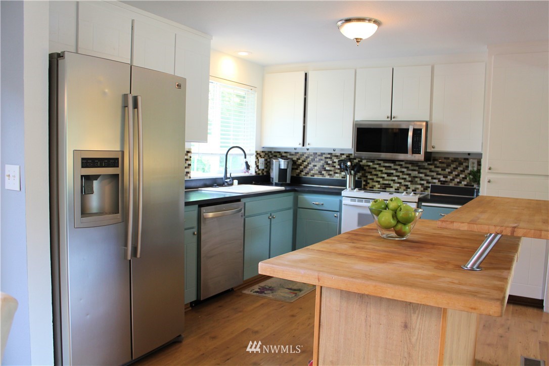 709 222nd Street Southwest Bothell, WA 98021 - Photo 5 of 38 a kitchen with stainless steel appliances kitchen island granite countertop a refrigerator a sink a stove a dining table and chairs