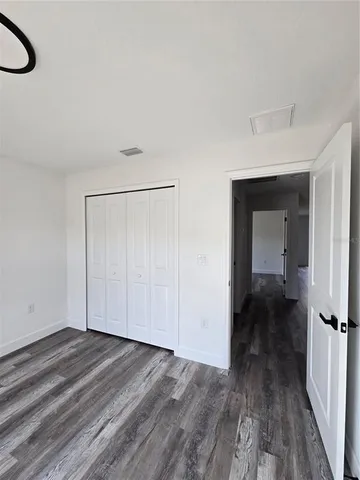 a view of a room with wooden floor a ceiling fan and windows