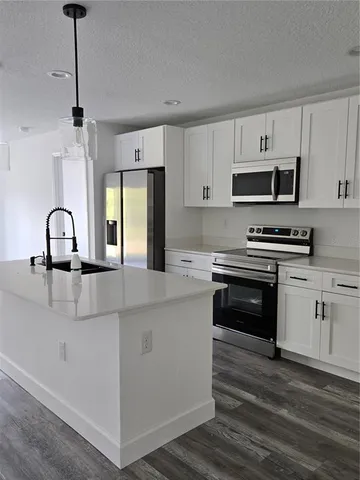 a kitchen with kitchen island granite countertop a stove a sink and a refrigerator