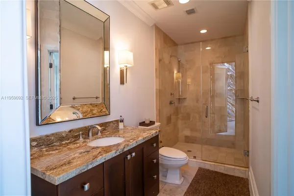 a bathroom with a granite countertop sink a toilet and shower