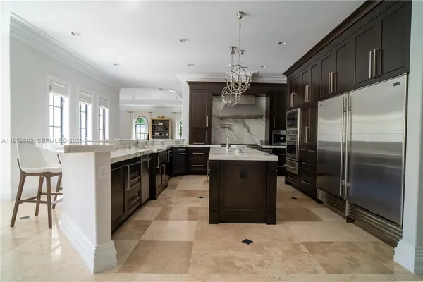 a large kitchen with kitchen island a chandelier and refrigerator
