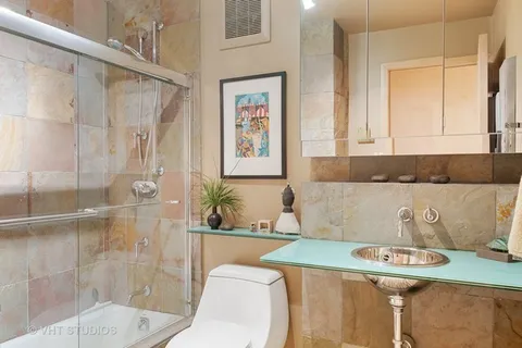 a bathroom with a granite countertop sink a toilet a mirror and shower