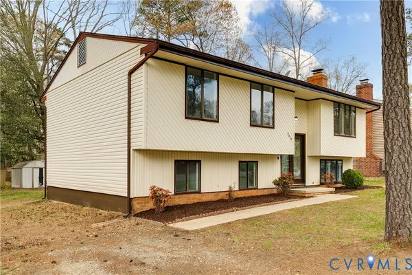 a view of a white house with a small yard and large tree