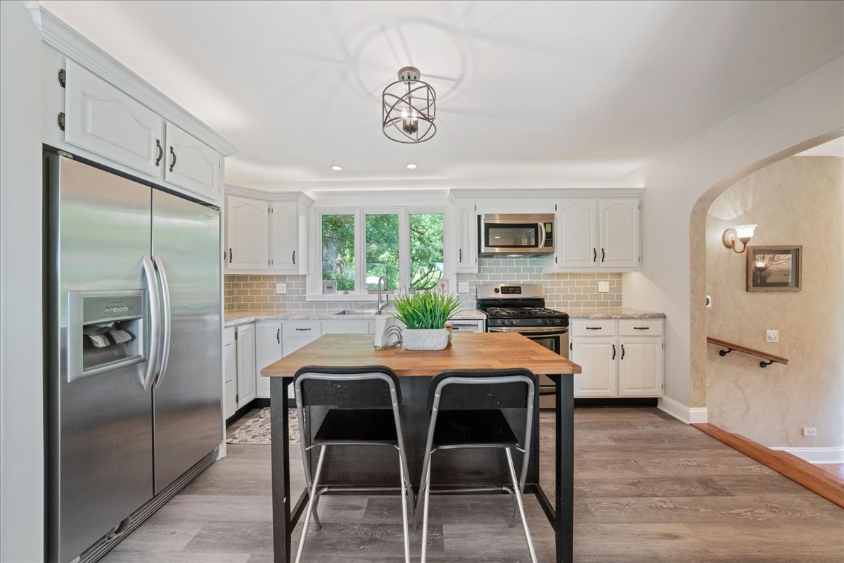 2N989 Beith Road Elburn, IL 60119 - Photo 9 of 35 a kitchen with stainless steel appliances granite countertop a refrigerator a stove a sink a dining table and chairs with wooden floor