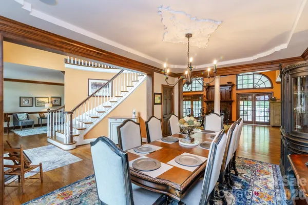 a dining room with wooden floor a chandelier a wooden table and chairs