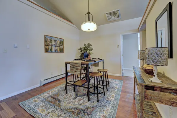 a dining room with wooden floor a chandelier a wooden table and chairs