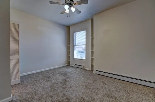 a view of an empty room with a chandelier fan