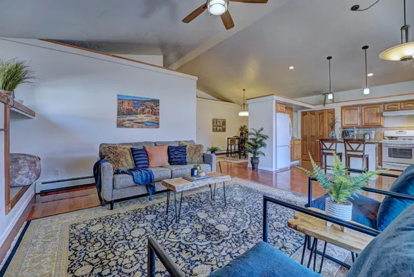a living room with furniture kitchen view and a chandelier