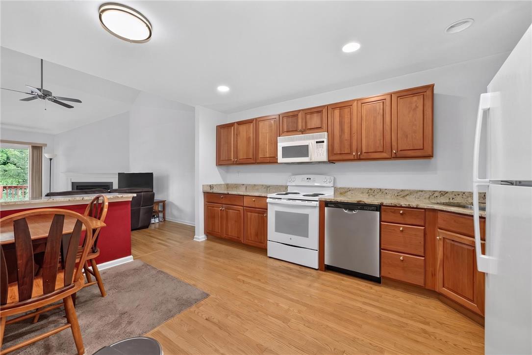 198 Park Ridge Drive Easton, PA 18040 - Photo 6 of 28 A well-equipped kitchen features wood cabinetry, granite counters, and light hardwood flooring, seamlessly flowing into the adjacent living space.