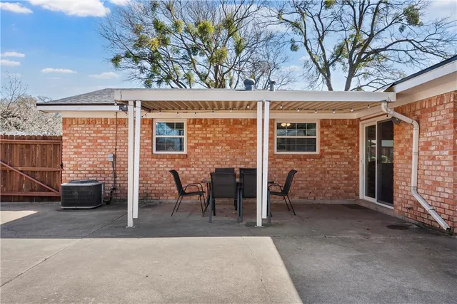 a view of a patio with table and chairs with wooden fence and large trees