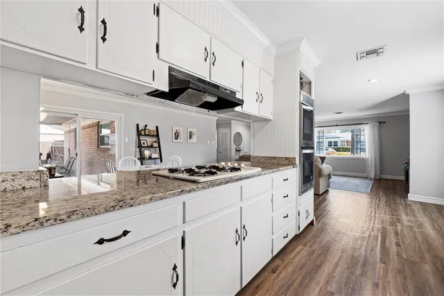 a large kitchen with stainless steel appliances granite countertop a lot of counter space and wooden floor